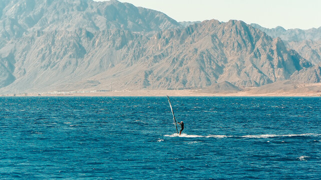 People enjoying water sports like windsurfing and kitesurfing on a sunny sea beach during a summer vacation