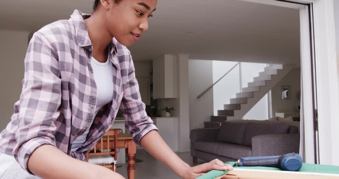 African American woman checking stretching fabric on frame at door using blue staple gun upholstery