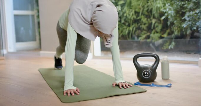Woman of African descent from plank driving alternating knees for core or cardio, kettlebell and hij
