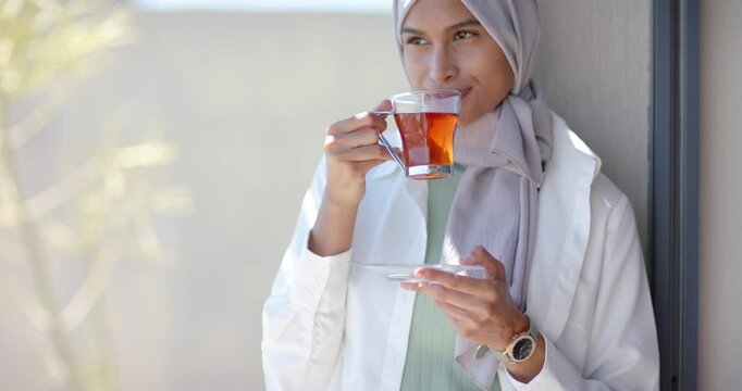 Woman wearing hijab watch adjusting grip on teacup sipping testing leaning on doorframe gazing left