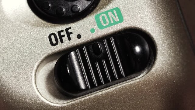 Close up of black power slider toggling off and on on metallic gold electronic device