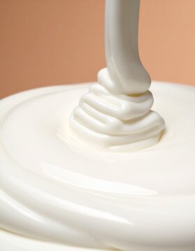 Glossy White Cream Swirl Pouring on Soft Beige Background