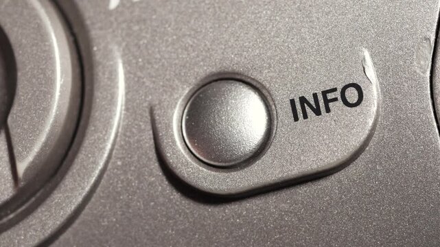 Macro close up of info button pressed on metallic silver panel with black lettering