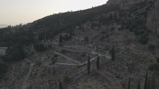 Aerial drone forward shot approaching the Temple of Apollo ruins in Delphi, Greece at sunset.