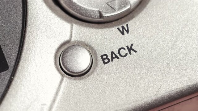 Macro close up of back button pressed on silver camera panel with black lettering