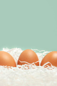 Three brown chicken eggs on blue background for Easter vertical
