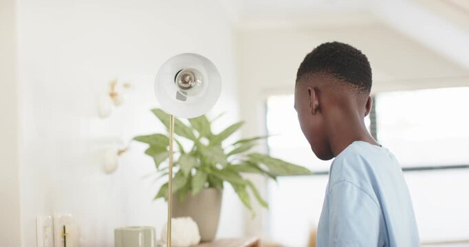African American teen boy fixing globe checking bulb lighting lamp at home miming power, copy space