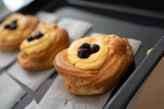 Close-up of a homemade St. Joseph's Zeppola, fresh from the oven, on a baking tray with parchment paper.