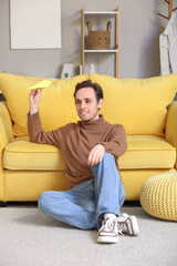 Obraz premium Young man throwing paper plane at home