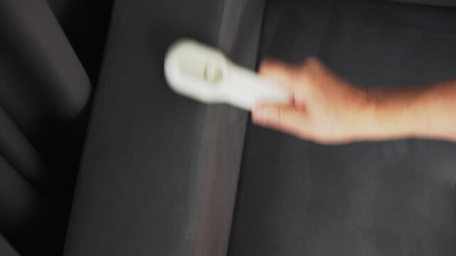 A person is using a brush to clean the surface of a gray chair.