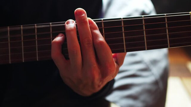 Fingers press guitar strings during a music practice session in a cozy indoor space