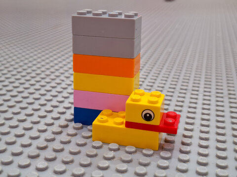 Assorted Lego plastic building blocks stacked in a tall tower and a small creative model on a grey baseplate for educational tutorial on March 28, 2026 in Bangkok, Thailand