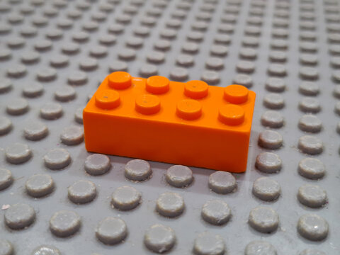 Single orange Lego style plastic construction brick placed on a matching baseplate for creative building and childhood educational on March 28, 2026 in Bangkok, Thailand