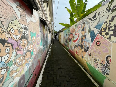 a wall full of artistic murals on a village street in the city of Semarang