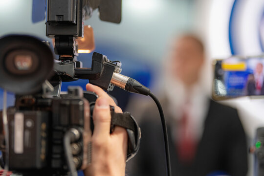 Recording an interview using a professional camera connected to an external audio cable. Integrated audio-video capture supports clear communication and accurate media reporting.