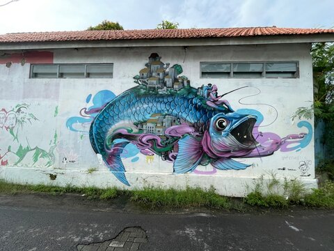 a wall full of artistic murals on a village street in the city of Semarang