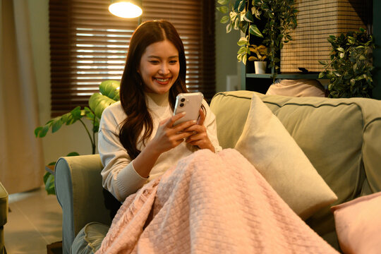 Asian Woman Enjoying Digital Life, Relaxing at Home with a Smartphone