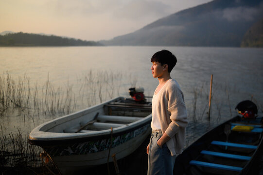 Peaceful travel scene of a young man looking across a misty lake, reflecting relaxation, adventure, and connection with nature