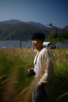 Lifestyle image of a young man with a camera in nature, capturing adventure, creativity, and a connection with scenic landscapes