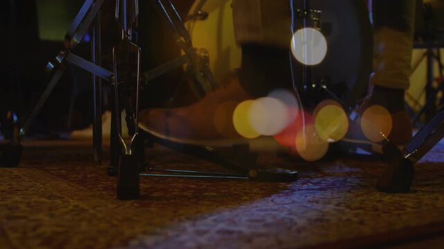 Drummer's foot starting heel lifting, pressing bass pedal for music rhythm, bokeh warming over foot