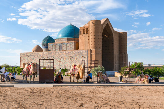 Turkistan, Kazakhstan - June 2, 2025: Closeup view of of camels waiting for tourists in front of the historical Mausoleum of Khoja Ahmed Yasawi (Hoca Ahmet Yesevi T&uuml;rbesi)