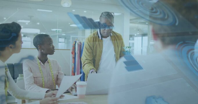 Lead touching laptop, guiding designers checking samples with blue overlays reflecting on glass