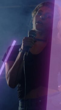Vertical video: Singer tilting head as purple neon tube sweeping, holding wired mic for music