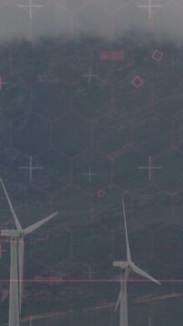 Vertical video: Gust pushing white turbines rotating on mountain ridge, hex grid tracking pink line
