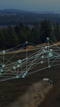 Vertical video: Tractor moving in plowed field, kicking dust, driving data net mapping farm data