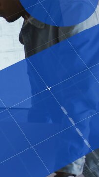 Vertical video: Man unrolling blueprint, blue overlays sliding over sheet inspecting design plans