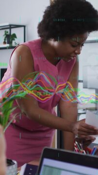 Vertical video: Woman in pink dress taking papers from peer as data graphs guiding business review
