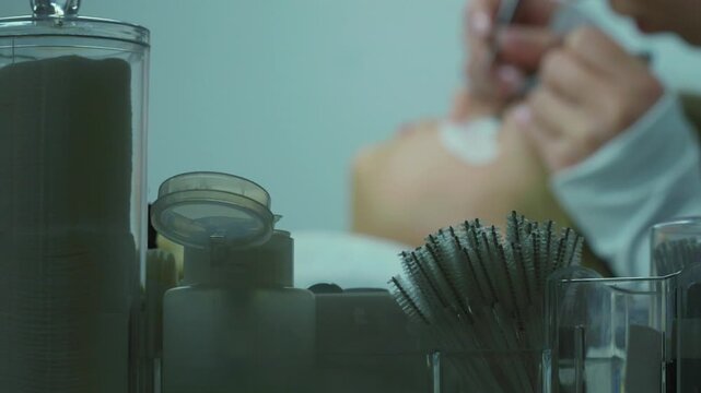 Close-up of professional applying eyelash extensions with precision tools
