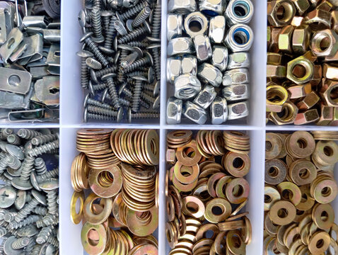 A variety of metal fasteners are neatly arranged in a compartment box, including screws, bolts, nuts, and washers in various sizes and types.