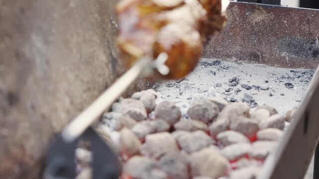 Cooking meat on a grill using charcoal and rotating the spit over the hot coals in a backyard setting