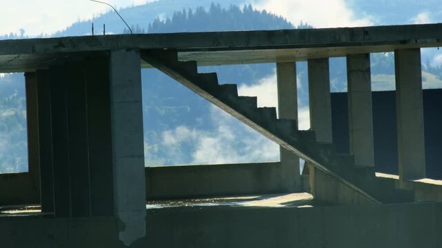Man in casual clothes walks inside unfinished building structure slow motion. Guy explores devasted hotel urbex spot at mountain valley