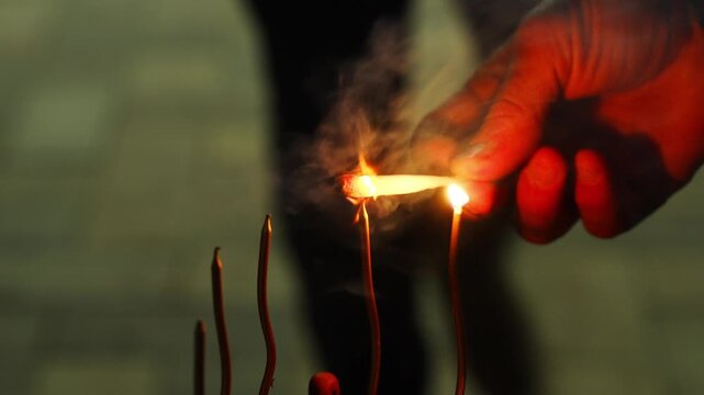 Lighting incense sticks in a temple setting during evening prayers in a serene environment with focused attention