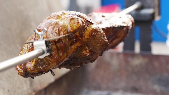 Slow cooking a large piece of meat on a rotating spit over open fire in a backyard
