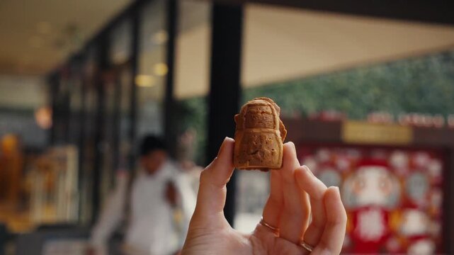 Woman's hand holding backpack-shaped ningyo-yaki cake in japan