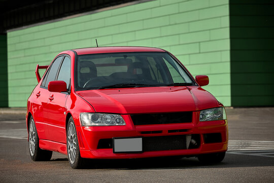 Red car on the street, sports sedan parked on an empty road with guardrails in daylight, no people