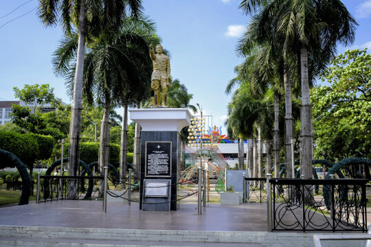 golden statue of general paulino santos stands on a black pedestal surrounded by tall palm trees in a park, general santos, mindanao, philippines 