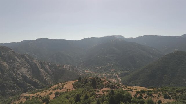 Aerial drone forward shot over green countryside landscape in Achaea, Peloponnese, Greece on a sunny day.