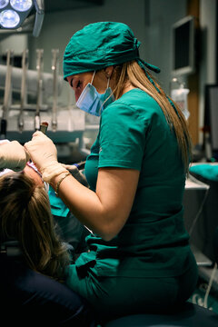 Female dentist in green scrubs treating a patient during a dental procedure in clinic