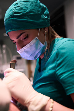 Female surgeon focused during surgery in operating room wearing mask and surgical scrubs