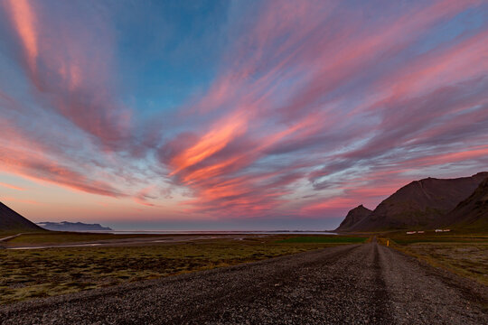 Arafed clouds leads toward distant peaks across Eastern Iceland under heavy, brooding skies