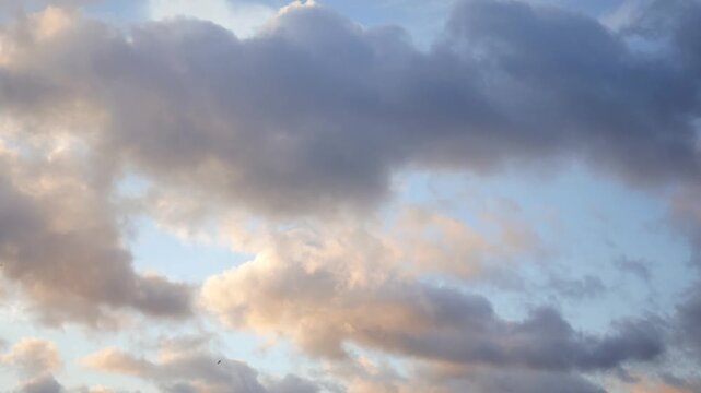 Beautiful time-lapse footage of clouds moving slowly across a vibrant blue sky during sunset.