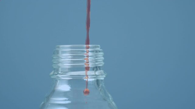 Animation of red shapes moving over liquid pouring into bottle on blue background