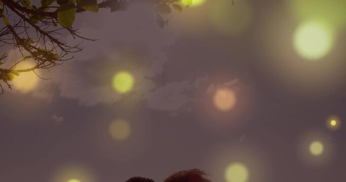 Glowing spots of light falling against african american couple kissing each other at the beach