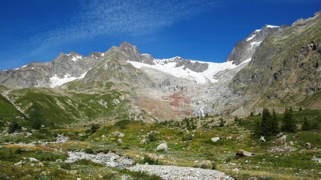 Panoramic view of high peaks, mountains and glaciers in Veny Valley, Aosta Valley, Italy, during a summer day. Blue sky with whith clouds on the background.