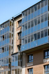 Fototapeta premium Modern Glass Balcony Apartment Building Facade With Brick Exterior and Urban Windows
