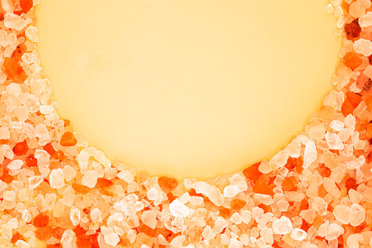 Pink Himalayan salt crystals semicircle border on yellow background with copy space